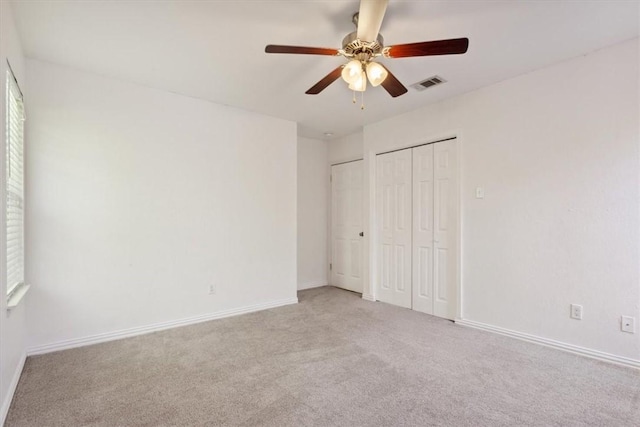 unfurnished bedroom with multiple closets, ceiling fan, and light colored carpet