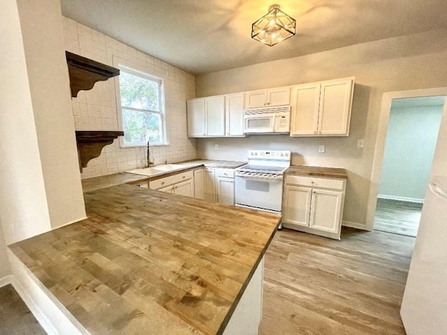 kitchen with butcher block countertops, white cabinets, white appliances, and sink