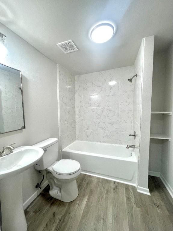 bathroom featuring hardwood / wood-style floors, tiled shower / bath combo, and toilet