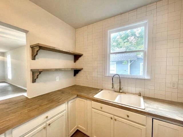 kitchen featuring butcher block countertops, tasteful backsplash, and sink