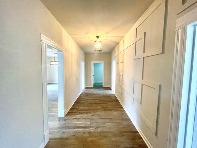 corridor featuring hardwood / wood-style flooring and an inviting chandelier