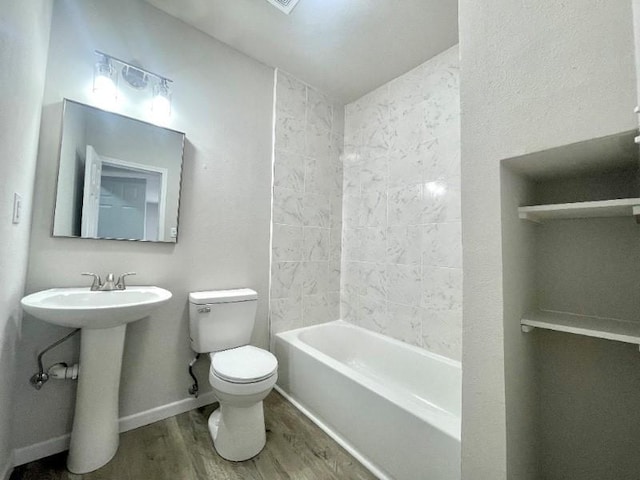 full bathroom with hardwood / wood-style flooring, toilet, tiled shower / bath, and sink