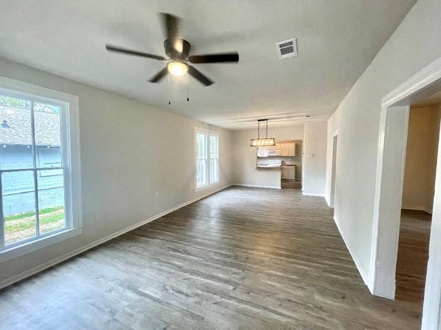 unfurnished living room featuring plenty of natural light, dark wood-type flooring, and ceiling fan