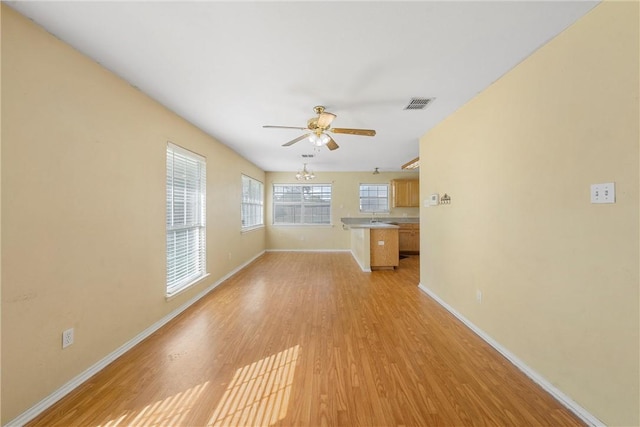 unfurnished living room featuring ceiling fan with notable chandelier, light hardwood / wood-style floors, and sink