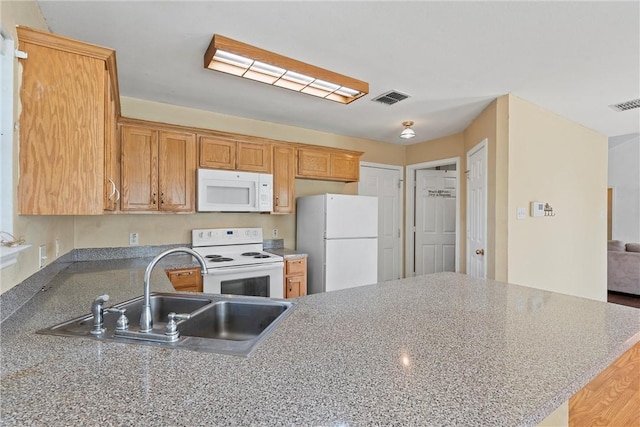 kitchen with kitchen peninsula, sink, and white appliances