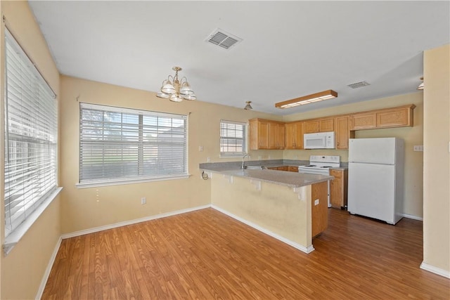 kitchen featuring white appliances, sink, light wood-type flooring, a notable chandelier, and kitchen peninsula