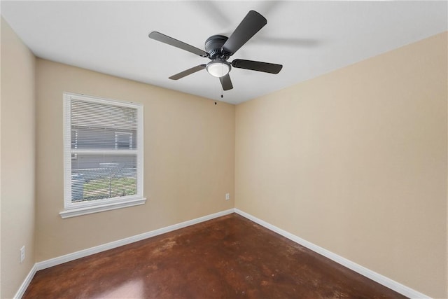 spare room with baseboards, concrete floors, and ceiling fan