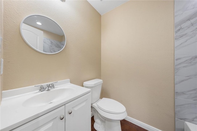 bathroom featuring vanity, toilet, a shower, and baseboards