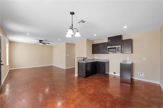 kitchen featuring stainless steel microwave, baseboards, visible vents, and finished concrete floors