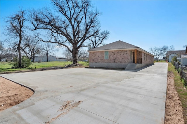 view of side of property featuring brick siding and concrete driveway