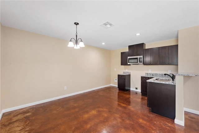 kitchen with baseboards, visible vents, dark brown cabinets, concrete flooring, and stainless steel microwave