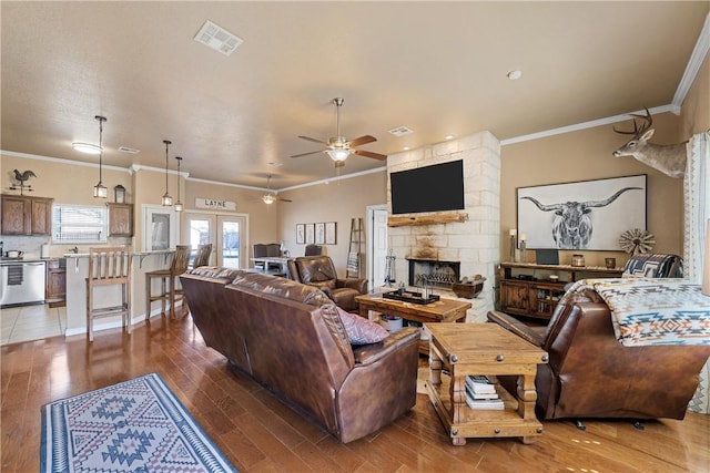 living room featuring crown molding, ceiling fan, a fireplace, and hardwood / wood-style floors