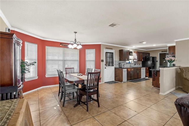 dining area featuring a chandelier, light tile patterned floors, ornamental molding, and sink