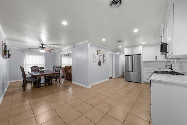 kitchen featuring stainless steel refrigerator, crown molding, light stone countertops, decorative backsplash, and white cabinets