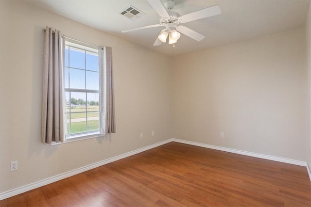 empty room featuring visible vents, ceiling fan, baseboards, and wood finished floors