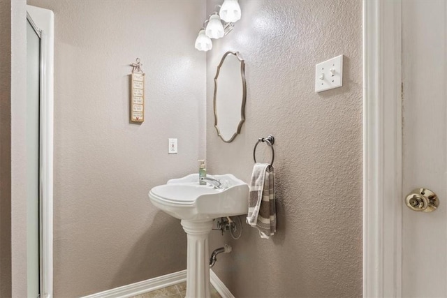 bathroom featuring a textured wall and baseboards