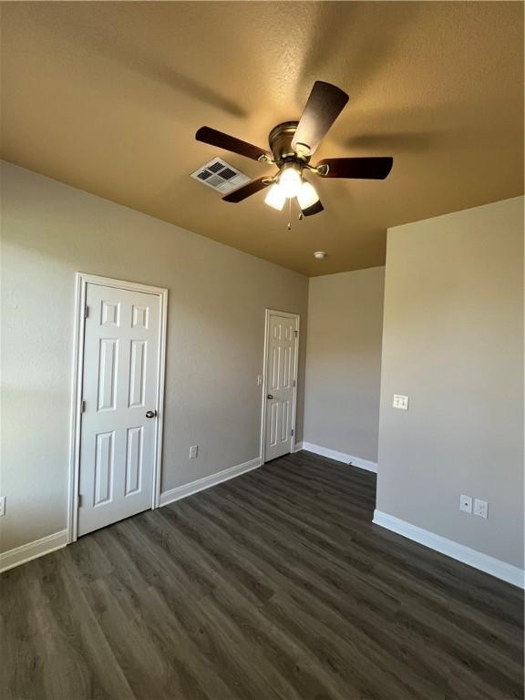 unfurnished bedroom with dark hardwood / wood-style flooring and ceiling fan