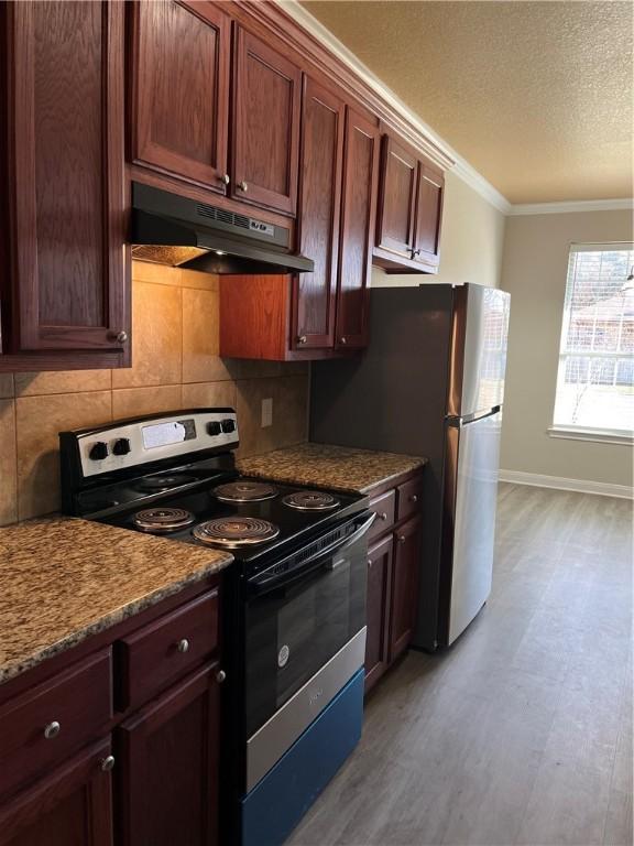 kitchen with light stone counters, light hardwood / wood-style flooring, decorative backsplash, appliances with stainless steel finishes, and ornamental molding