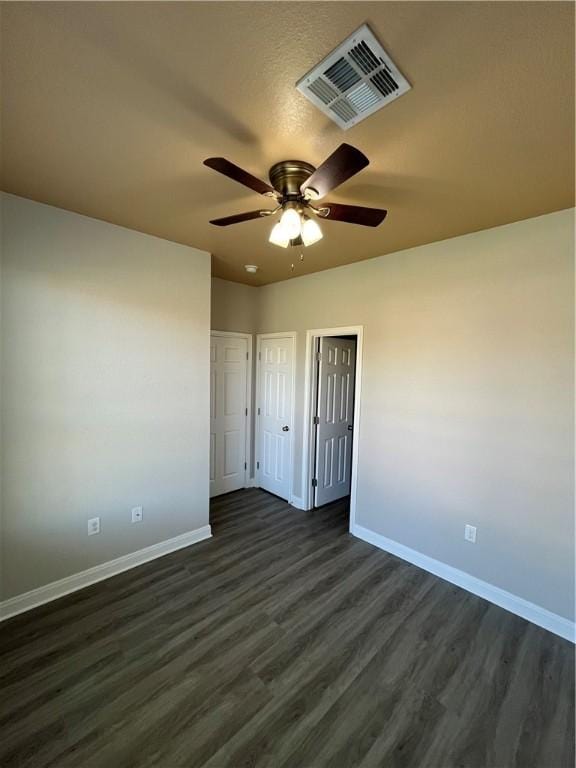 unfurnished bedroom with ceiling fan and dark wood-type flooring