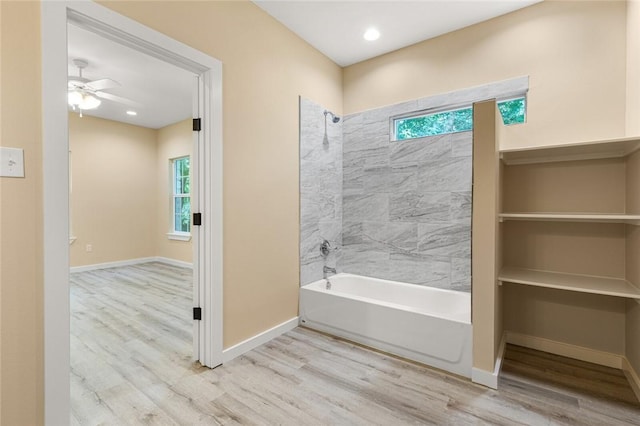 bathroom featuring a wealth of natural light, hardwood / wood-style floors, ceiling fan, and tiled shower / bath combo