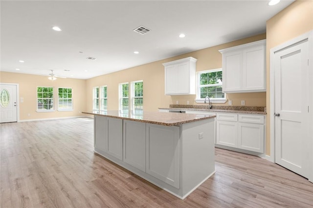 kitchen with white cabinets, plenty of natural light, ceiling fan, and a center island