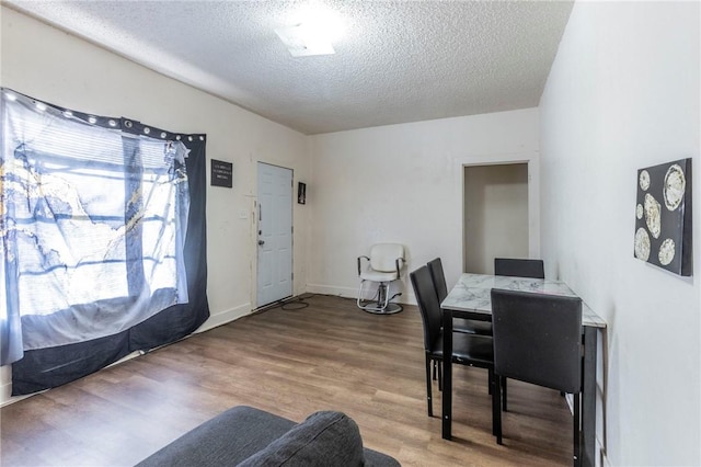 dining room with wood-type flooring and a textured ceiling