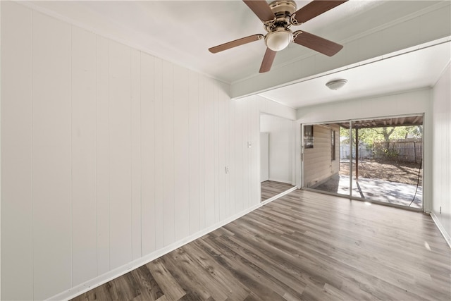 unfurnished room with ceiling fan, wooden walls, wood-type flooring, and ornamental molding