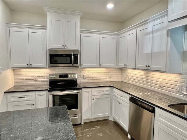 kitchen featuring white cabinets, decorative backsplash, dark stone countertops, and stainless steel appliances