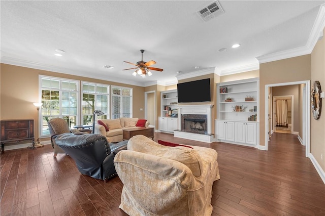 living room featuring dark wood-type flooring, built in features, ceiling fan, and crown molding