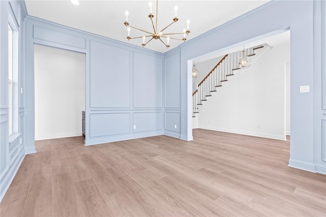 interior space with a notable chandelier, light wood-type flooring, and ornamental molding