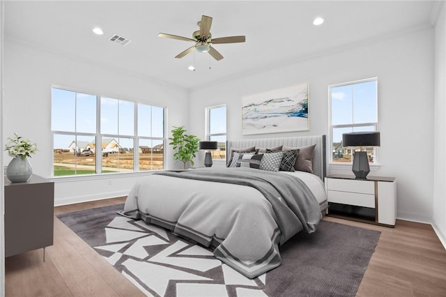 bedroom with ceiling fan, dark wood-type flooring, and multiple windows