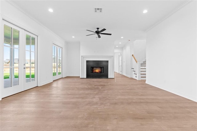 unfurnished living room featuring crown molding, french doors, and light hardwood / wood-style floors