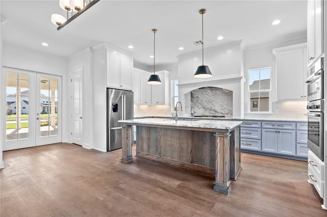 kitchen with white cabinets, decorative light fixtures, a healthy amount of sunlight, and a center island with sink