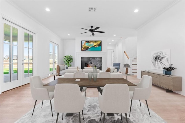 dining area featuring ceiling fan, light wood-type flooring, ornamental molding, and french doors