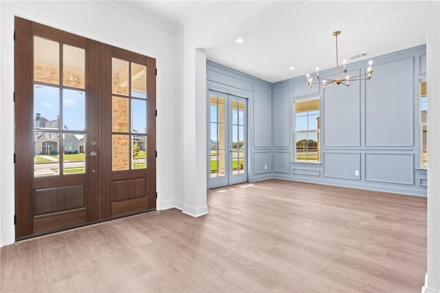 entryway featuring french doors, plenty of natural light, a notable chandelier, and hardwood / wood-style floors