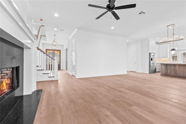 living room featuring ceiling fan with notable chandelier, light hardwood / wood-style flooring, and crown molding