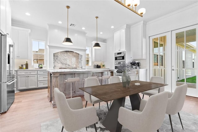 dining space featuring french doors, light wood-type flooring, and crown molding