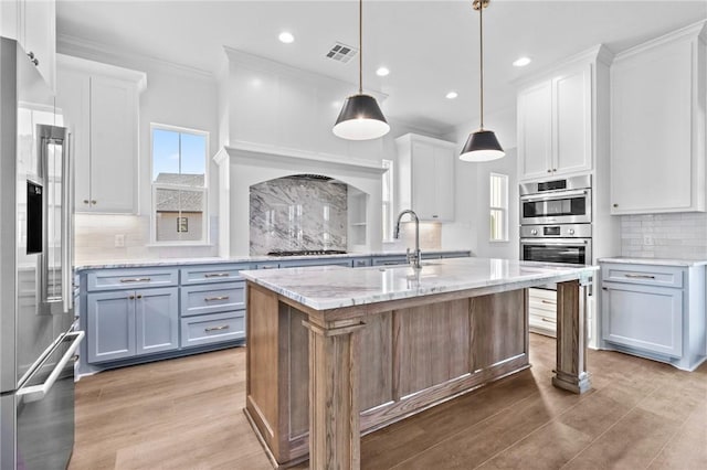 kitchen featuring white cabinets, stainless steel appliances, and a kitchen island with sink