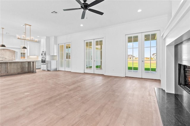 unfurnished living room with a premium fireplace, ceiling fan, french doors, and light hardwood / wood-style floors