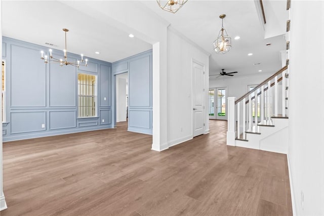 unfurnished living room with crown molding, hardwood / wood-style floors, and ceiling fan with notable chandelier