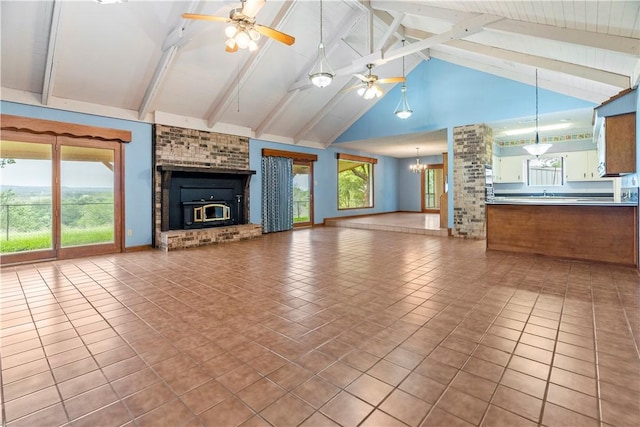 unfurnished living room with a wealth of natural light, high vaulted ceiling, ceiling fan with notable chandelier, and light tile patterned floors