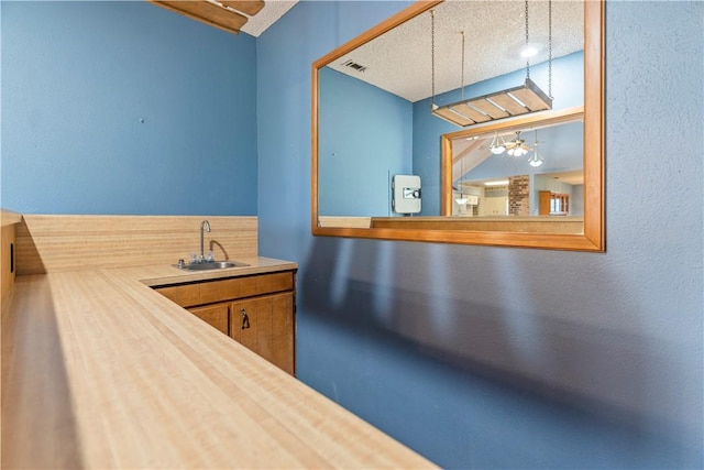 kitchen with wood counters, a textured ceiling, and sink