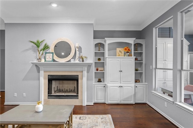 living room featuring a tiled fireplace, dark wood-type flooring, and ornamental molding