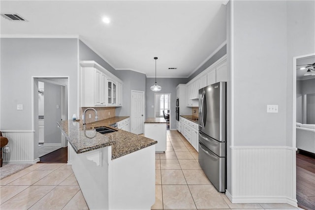 kitchen featuring white cabinetry, decorative light fixtures, light tile patterned floors, stainless steel fridge, and kitchen peninsula