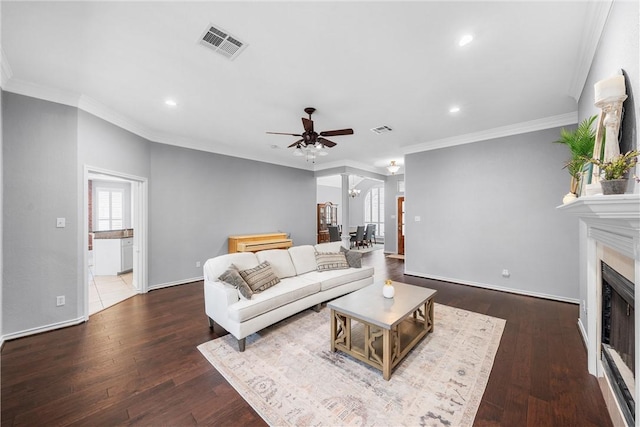 living room with ornamental molding, ceiling fan with notable chandelier, a wealth of natural light, and dark hardwood / wood-style flooring