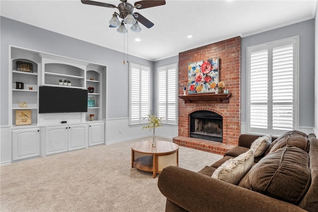 carpeted living room featuring ceiling fan, ornamental molding, a brick fireplace, and built in features