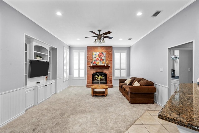 living room featuring ceiling fan, light colored carpet, ornamental molding, and a fireplace