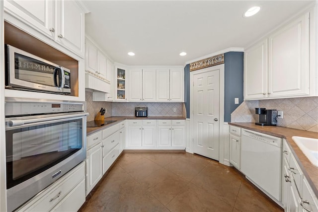 kitchen featuring dark tile patterned flooring, white cabinetry, appliances with stainless steel finishes, and tasteful backsplash