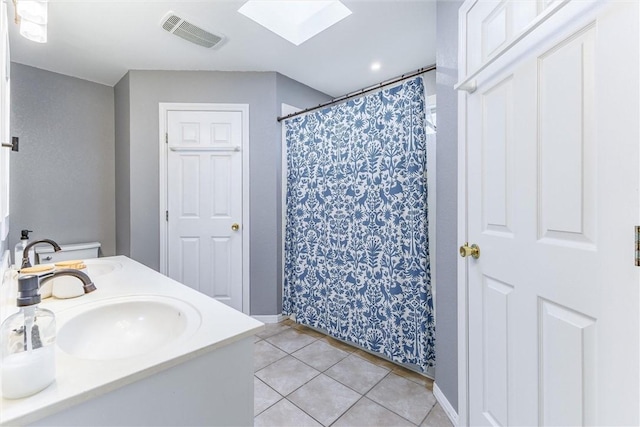 bathroom featuring tile patterned flooring, walk in shower, vanity, and a skylight