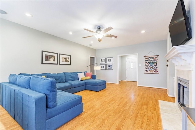 living room featuring a tiled fireplace, wood-type flooring, and ceiling fan